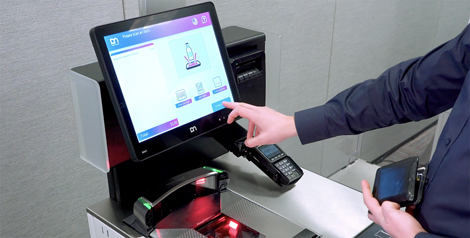 Close up of hands interacting with a touchscreen kiosk to represent Vynamic self-service touchpoint retail POS software