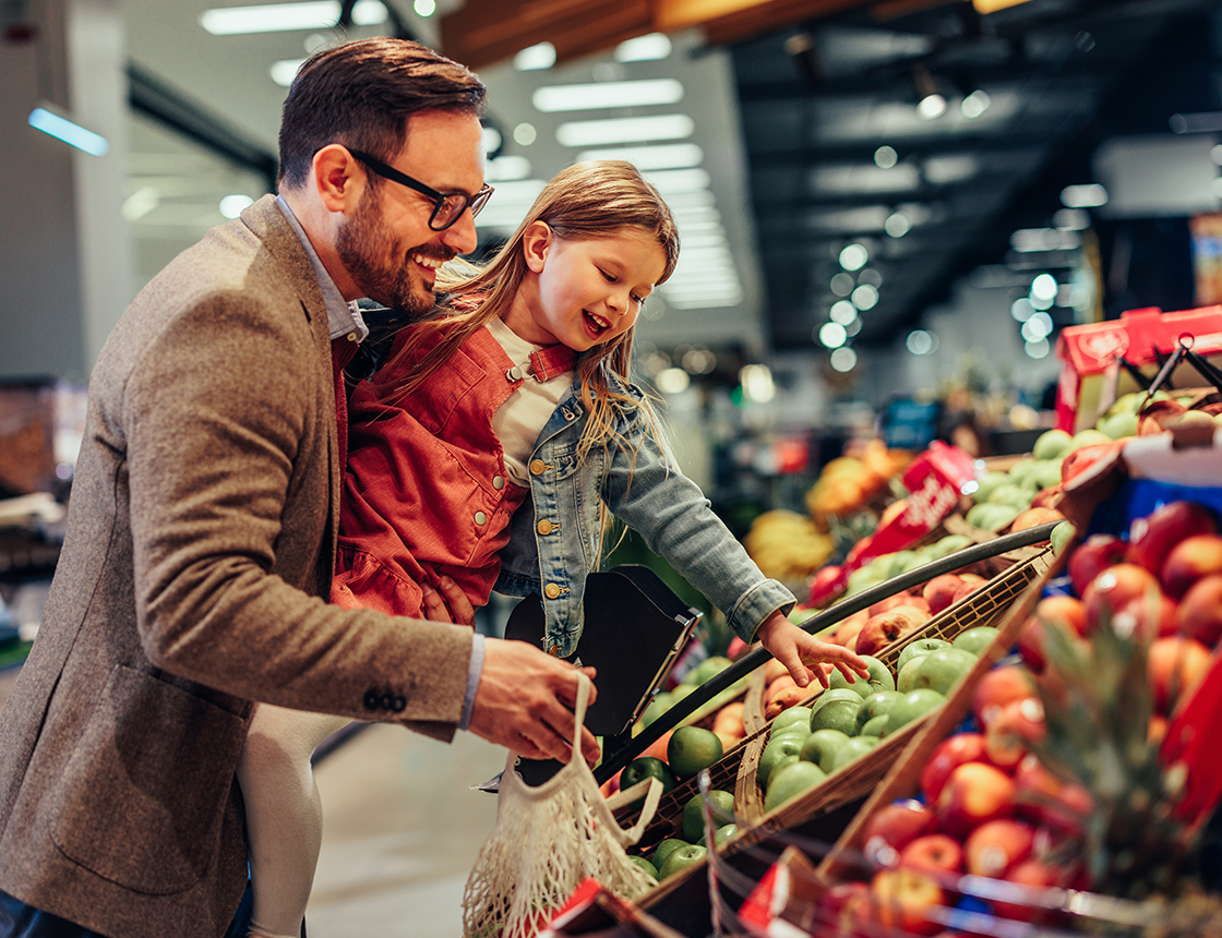 Father and daughter picking out produce at grocery store