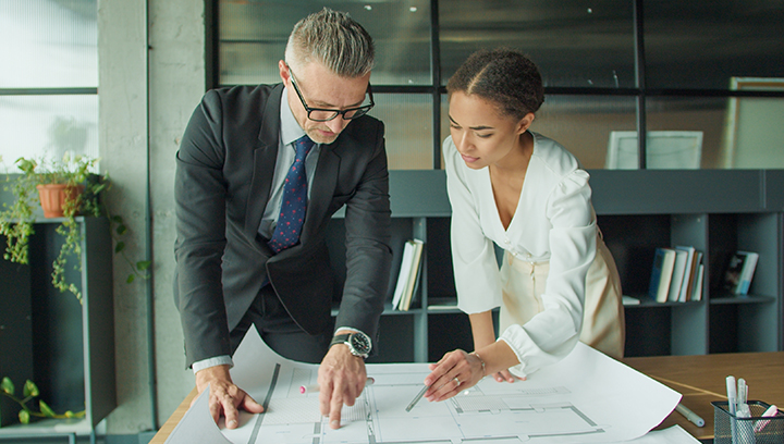 2 individuals looking over architectural drawings