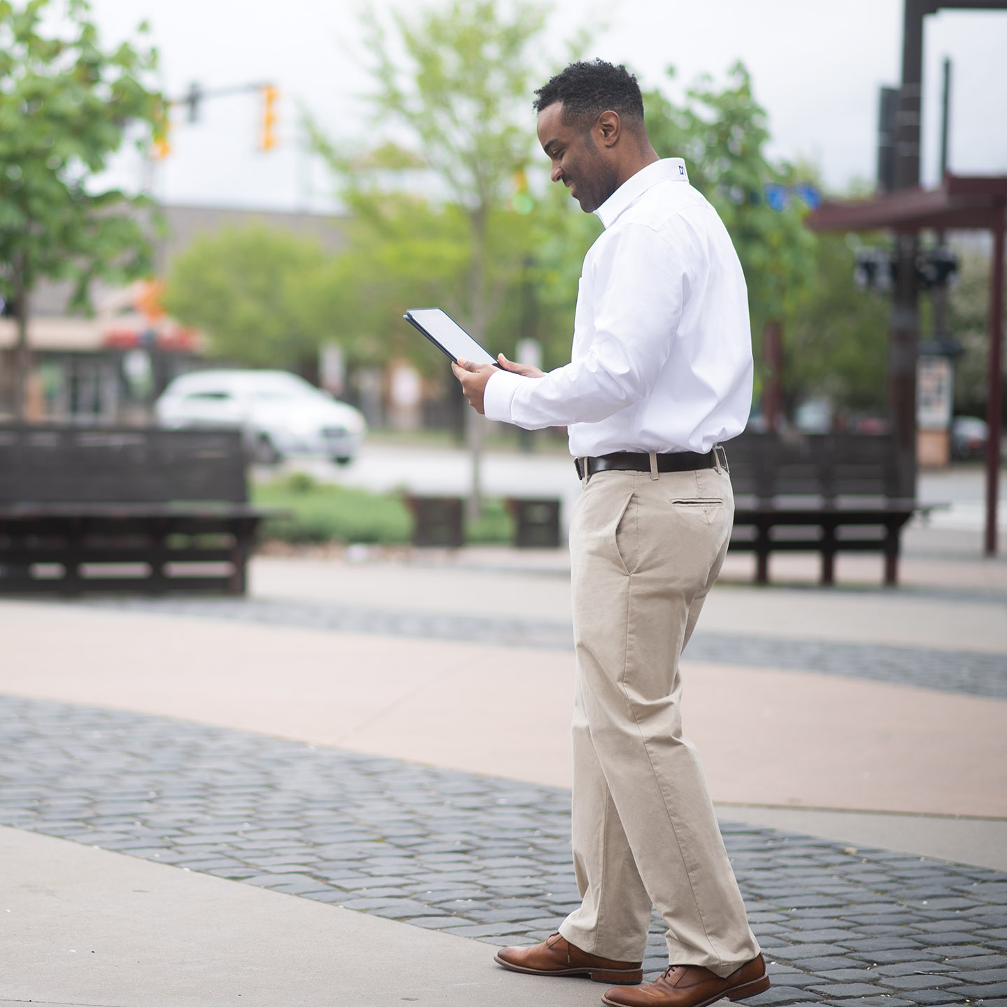 A Diebold Nixdorf service representative smiles as he looks at a tablet