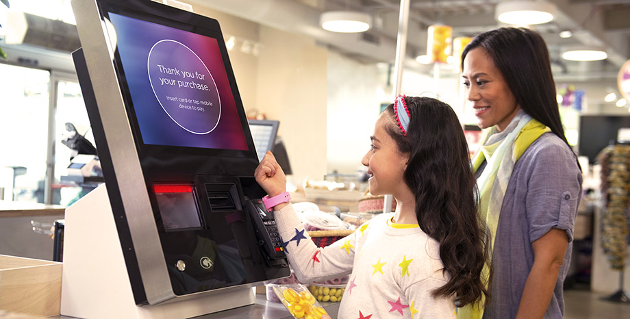 Mother and daughter check out at a self-service kiosk using a smart watch